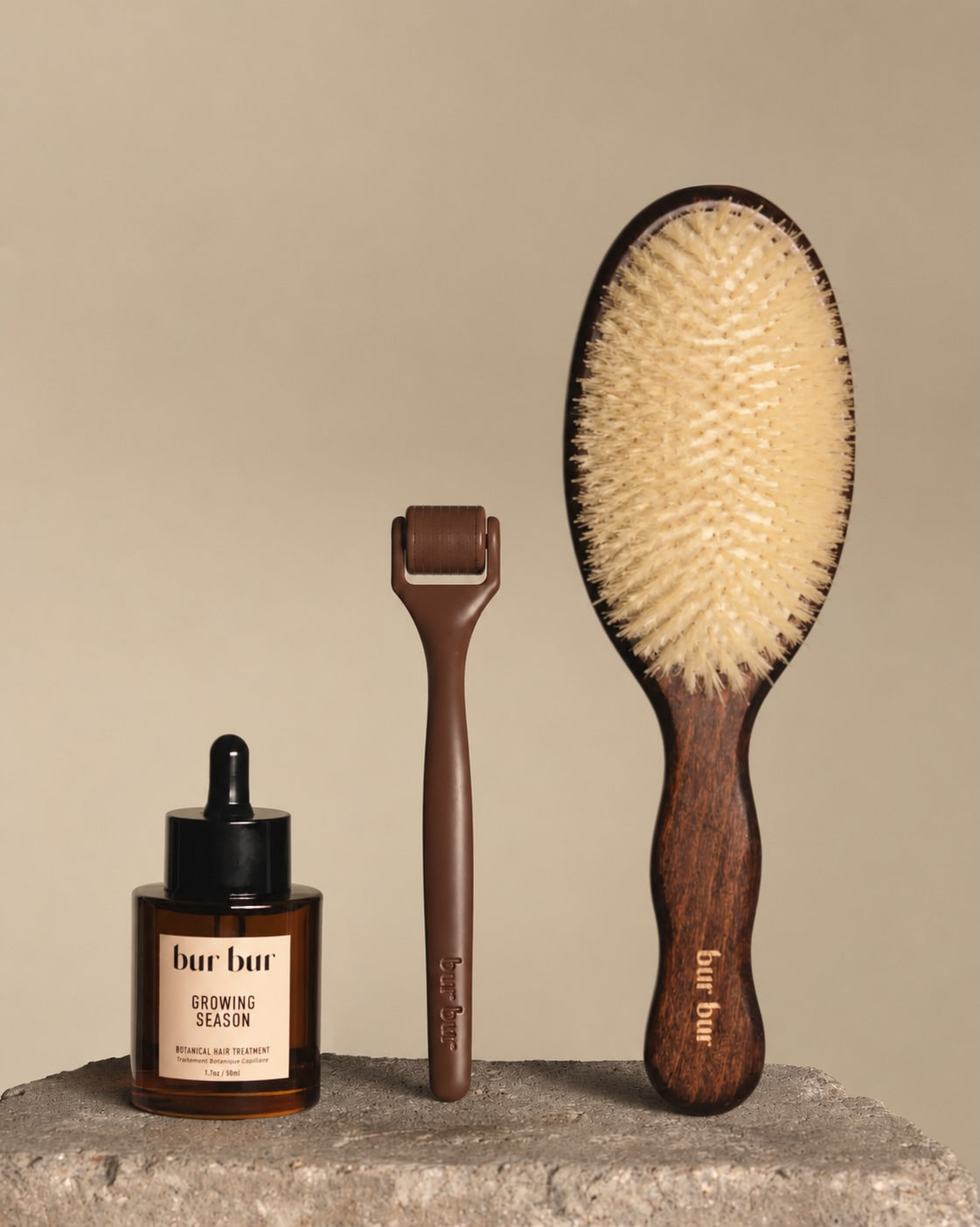 Three 'bur bur' hair care products on a stone surface with a beige background