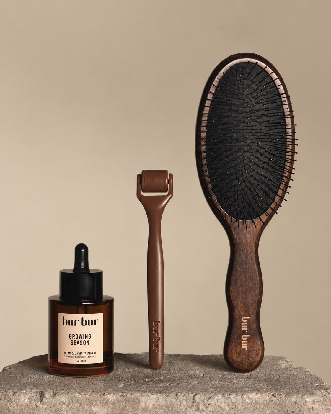 Three 'bur bur' hair care products on a stone surface with a beige background
